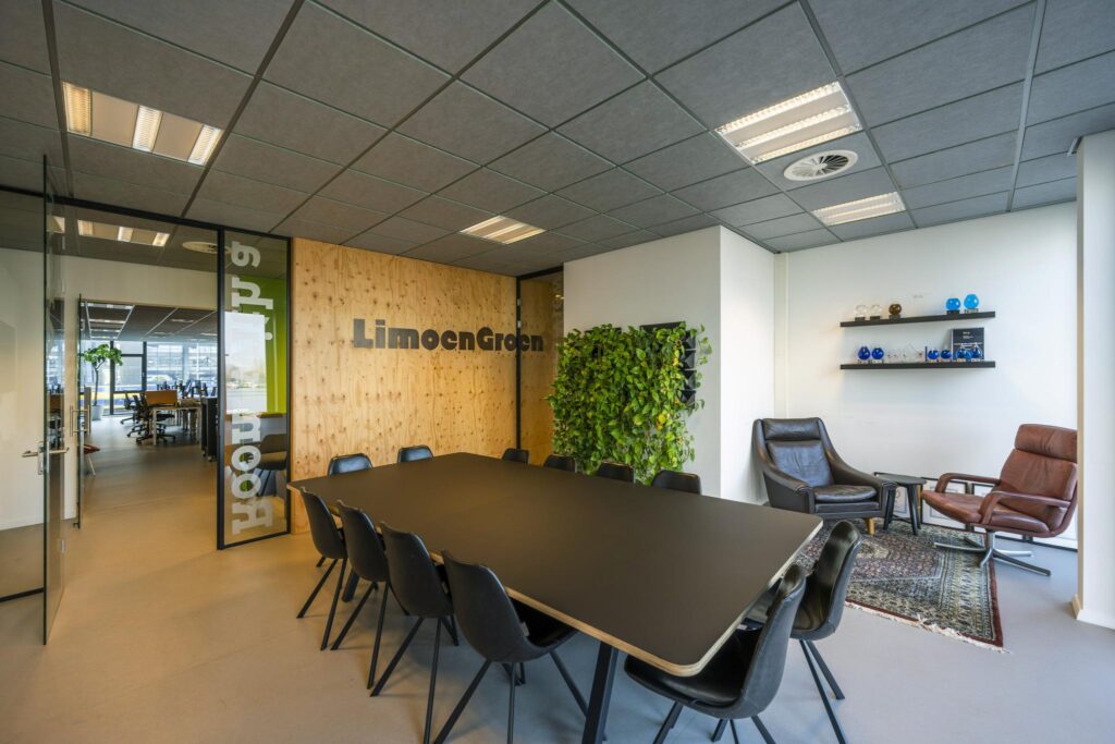 Vergaderruimte van LimoenGroen aan de De Ruijterkade met zwarte tafel, plantenwand en zithoek.